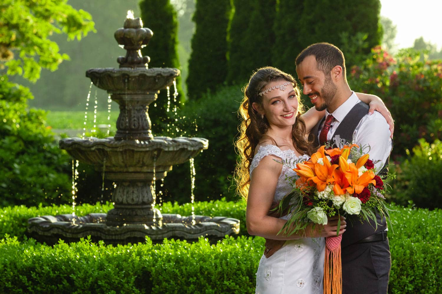 Bride and groom pose next to the fountain at Laurel Creek Manor during golden hour.