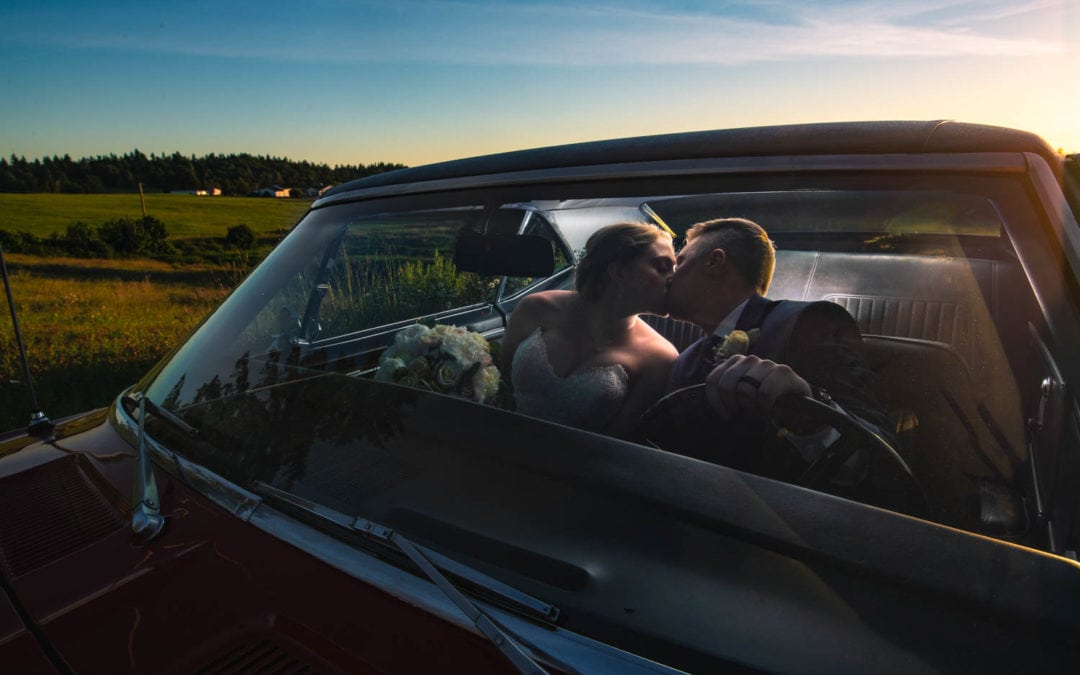 Bride and groom kiss in a classic car