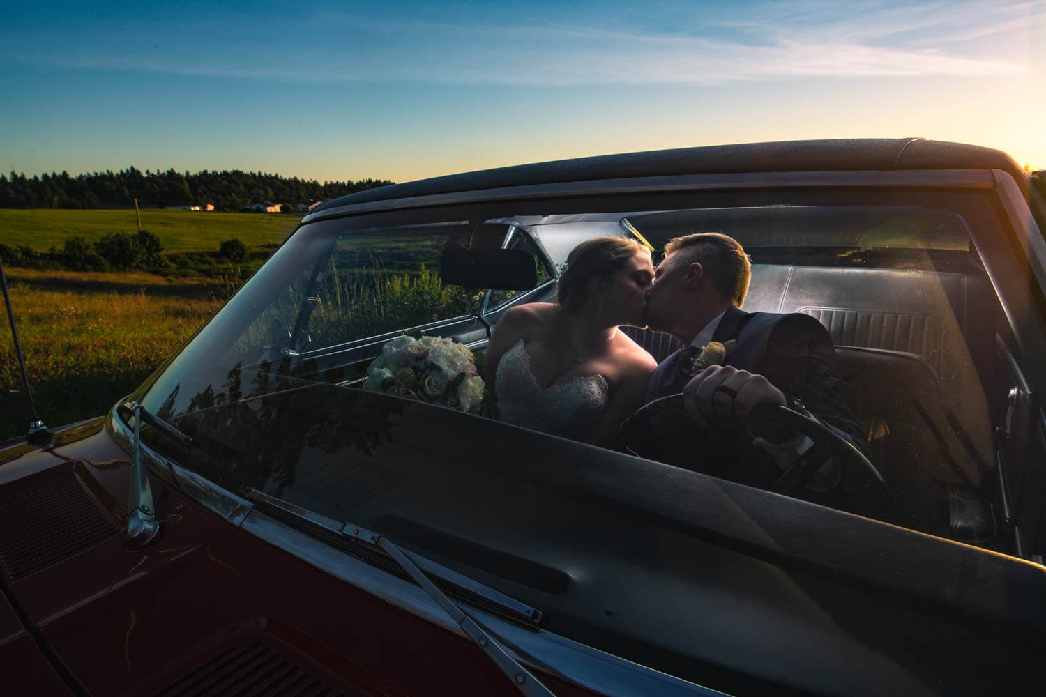Bride and groom kiss in a classic car