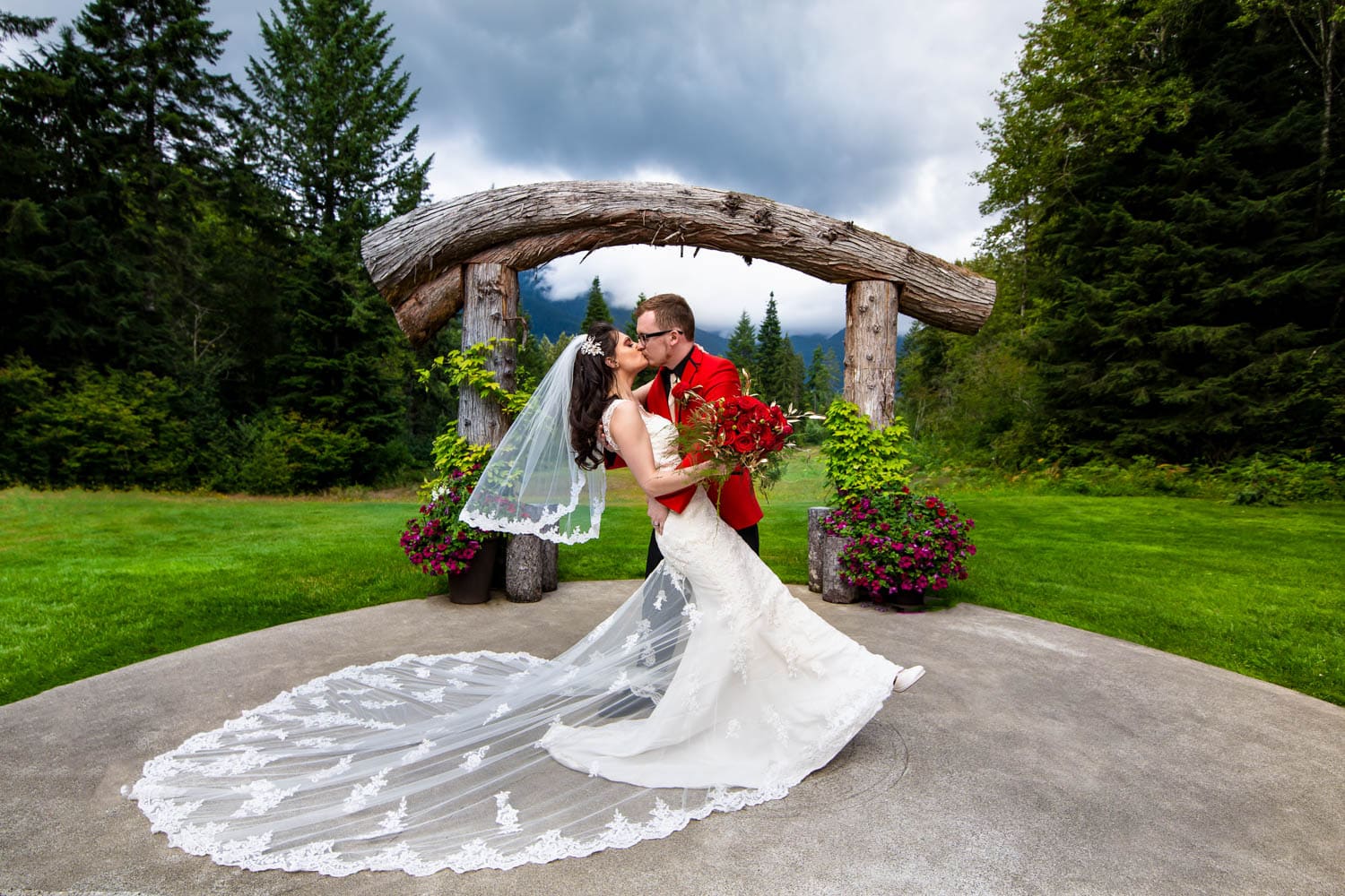 Bride and Groom kiss in front of the wedding arch at Nisqually Winds Mountain House near Mt. Rainier.