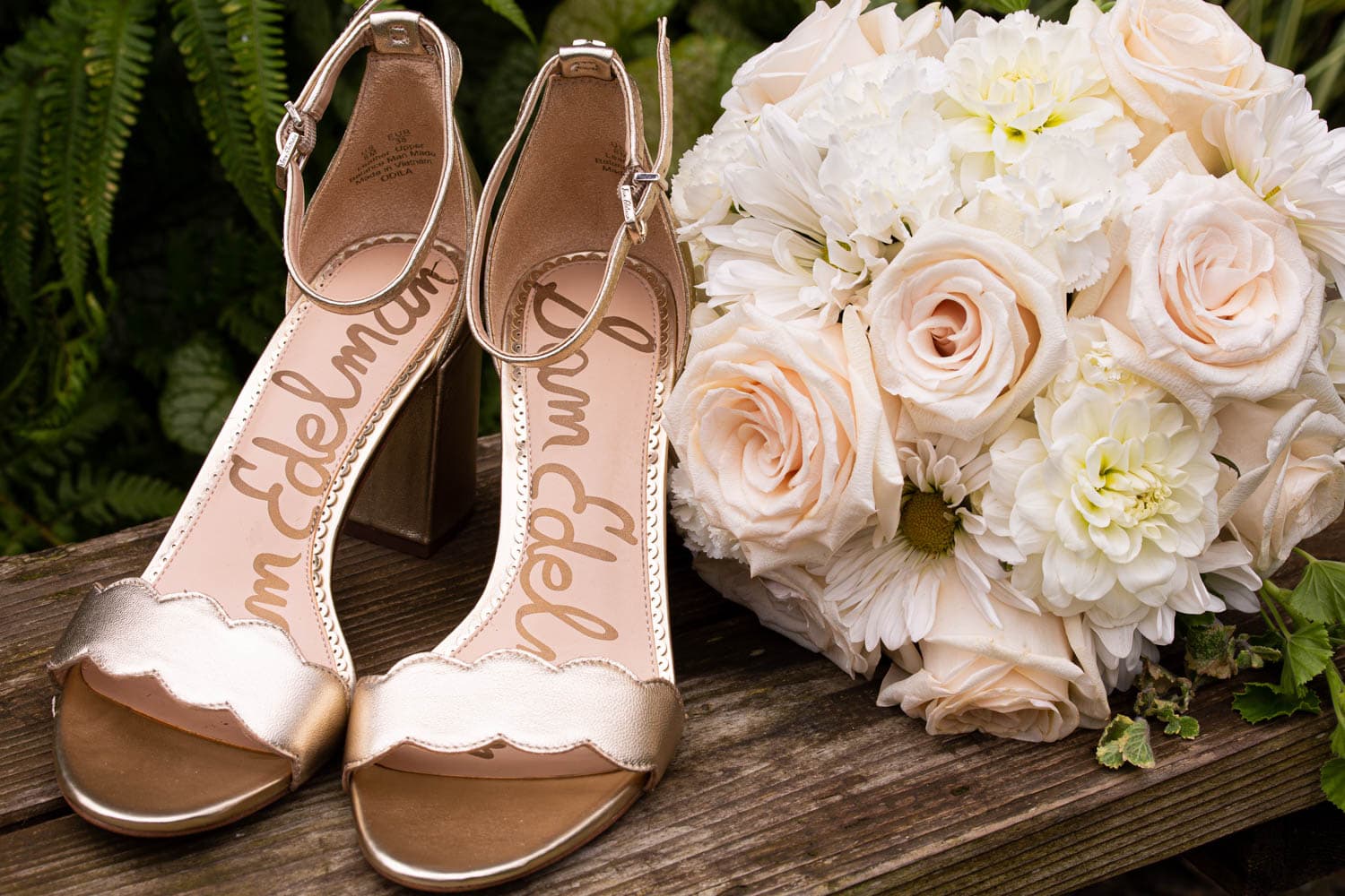 Wedding detail shot of the bride's gold platform sandals and white and blush bouquet with roses, dahlias, and daisies.