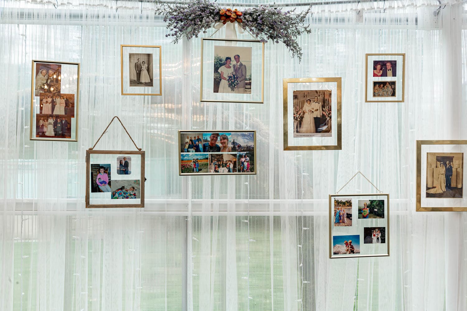 Wedding day photo wall with floating frames on a white curtained wall.