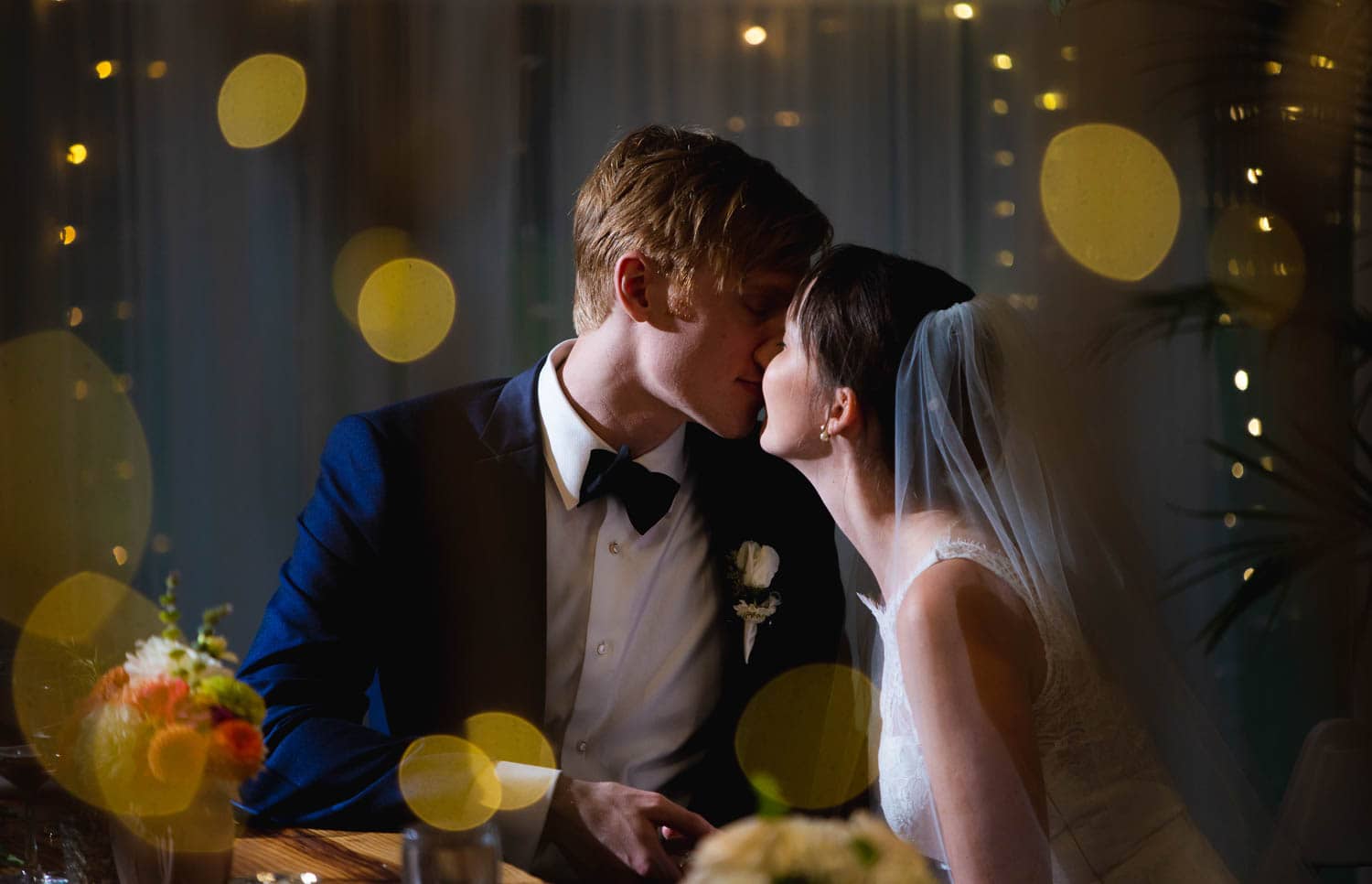 With twinkly lights around them, the bride and groom share a kiss with dramatic lightning during their reception.