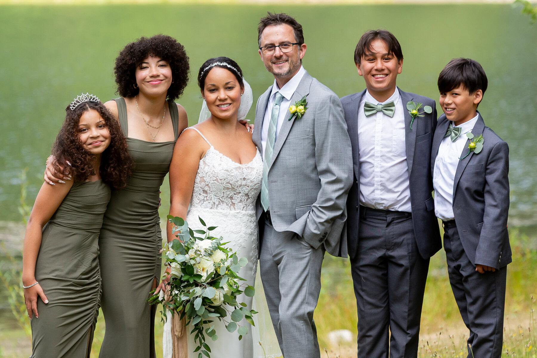 Formal wedding portrait of a blended family dressed in elegant formal attire outdoors.
