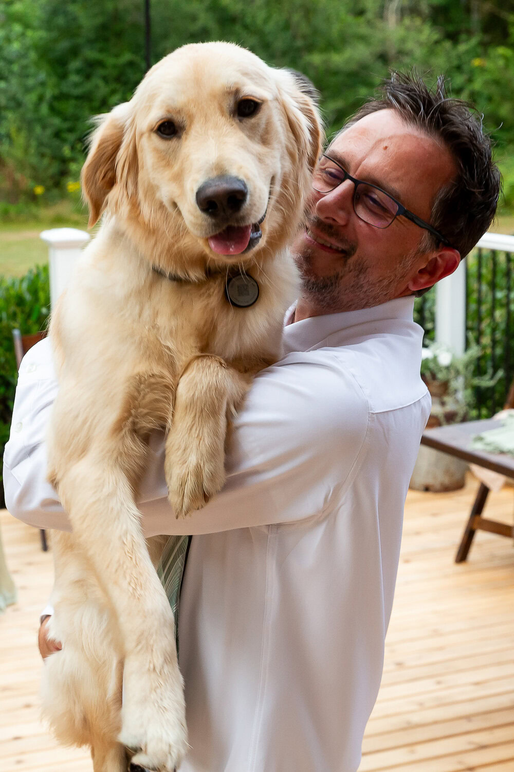 Golden retriever in man's arms at outdoor event, joyful pet and owner bonding, pet photography for dog lovers.